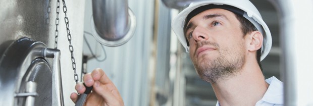 harter Wettbewerb bei arbeitsintensiven Produkten und Dienstleistungen; Arbeitskosten in Bayern senken Arbeiter steht vor einer Maschine und betätigt diese